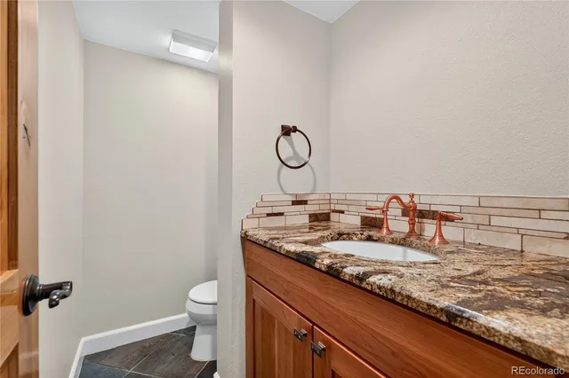 a bathroom with a granite countertop sink a toilet and a mirror