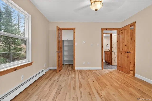 a view of empty room with wooden floor and fan