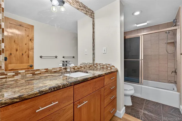 a bathroom with a granite countertop sink toilet and shower