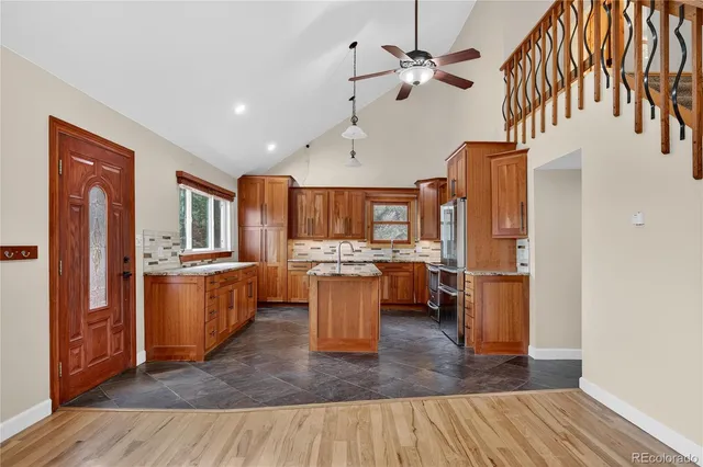 a kitchen with stainless steel appliances granite countertop a refrigerator a sink dishwasher a stove and white countertops with wooden floor