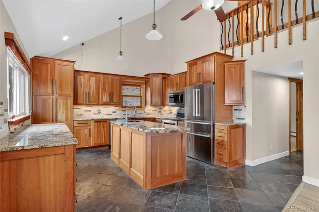 a kitchen with stainless steel appliances granite countertop a refrigerator a stove and a sink