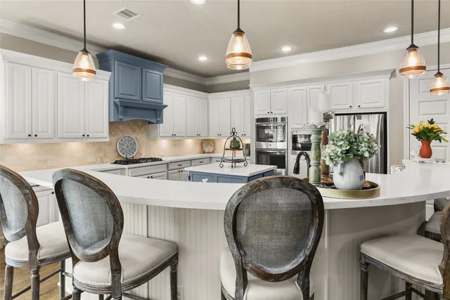 a kitchen with stainless steel appliances granite countertop a sink a stove a kitchen island with chairs and white cabinets