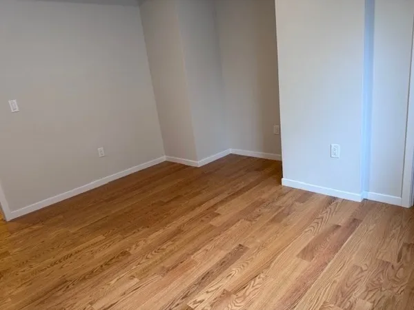 an empty room with wooden floor and a window
