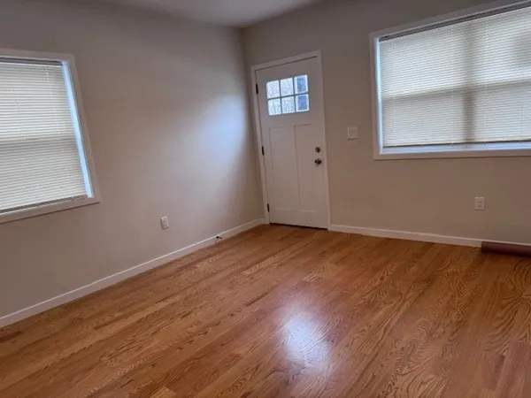 a view of an empty room with wooden floor and a window