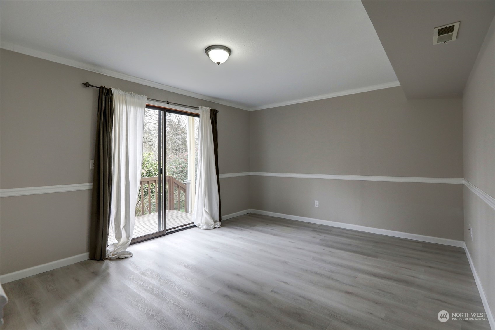 12404 Southeast 227th Street Kent, WA 98031 - Photo 14 of 21 an empty room with wooden floor and windows with curtains