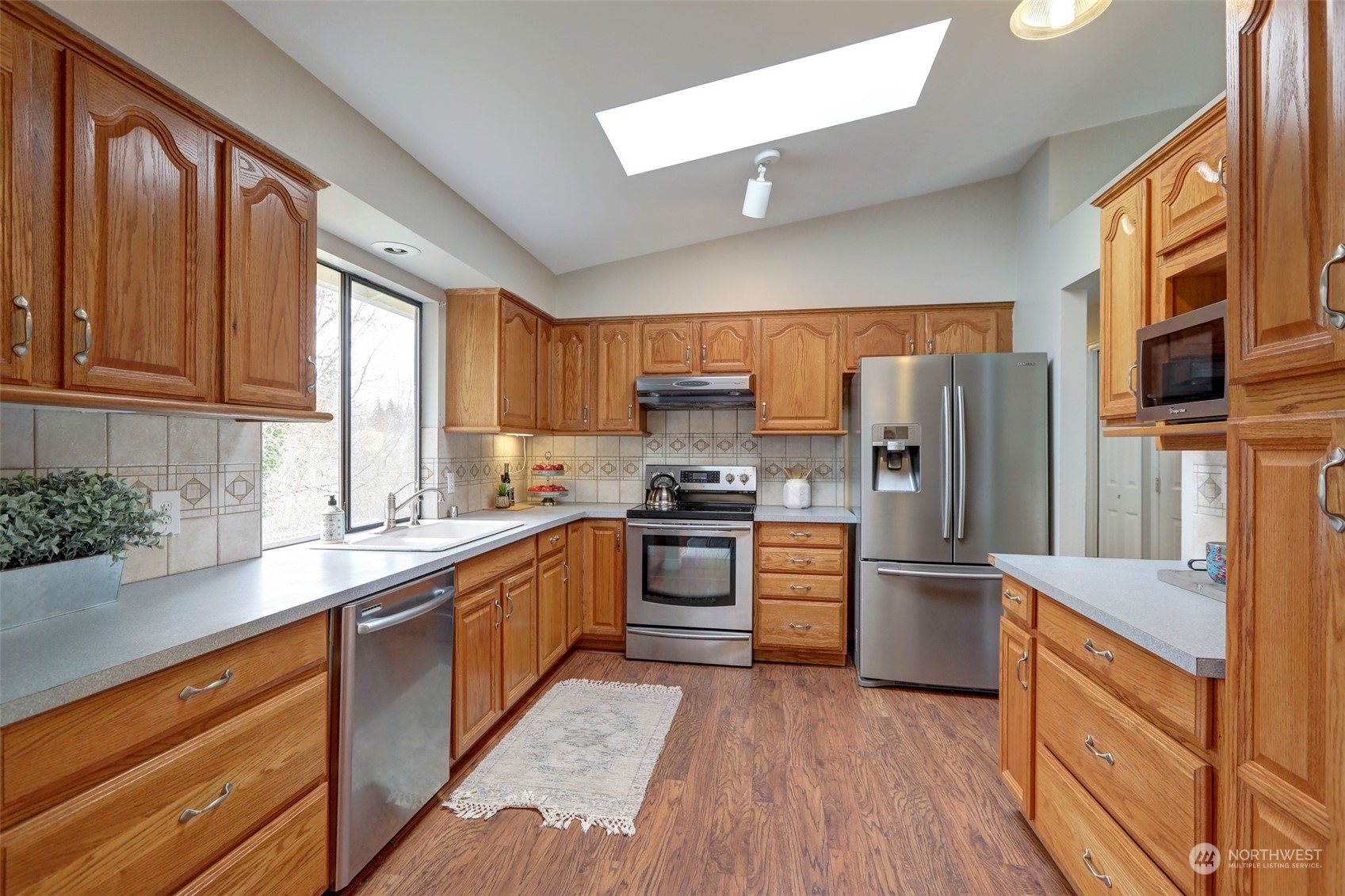 12404 Southeast 227th Street Kent, WA 98031 - Photo 6 of 21 a kitchen with stainless steel appliances granite countertop a refrigerator a stove top oven a sink and dishwasher with wooden floor