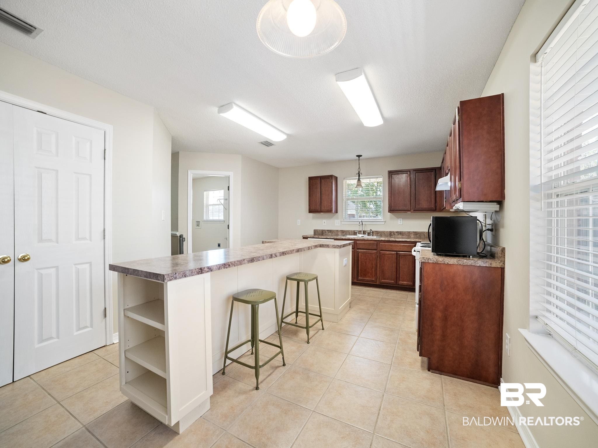 8320 Milton Road Mobile, AL 36695 - Photo 7 of 27 Kitchen with a breakfast bar, custom range hood, light tile patterned floors, decorative light fixtures, and a kitchen island