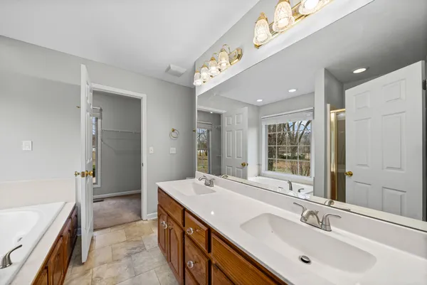 a spacious bathroom with a double vanity sink a large mirror and a bathtub