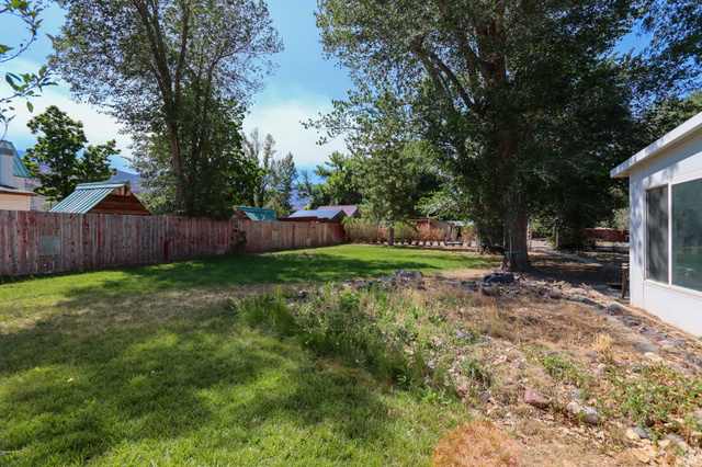 270 East 100 North Monroe, UT 84754 - Photo 41 of 65 Expansive backyard featuring a manicured lawn, established trees, and a wooden privacy fence