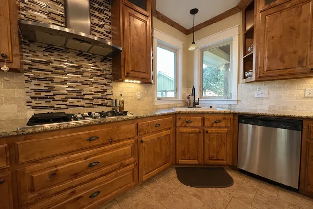 a kitchen with stainless steel appliances granite countertop a sink a stove and cabinets
