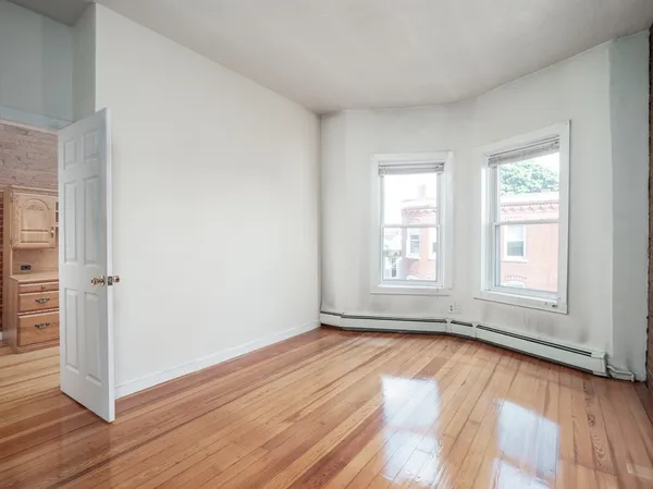 an empty room with wooden floor and windows