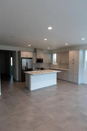 a large kitchen with kitchen island a stove a sink dishwasher and a refrigerator with wooden floor