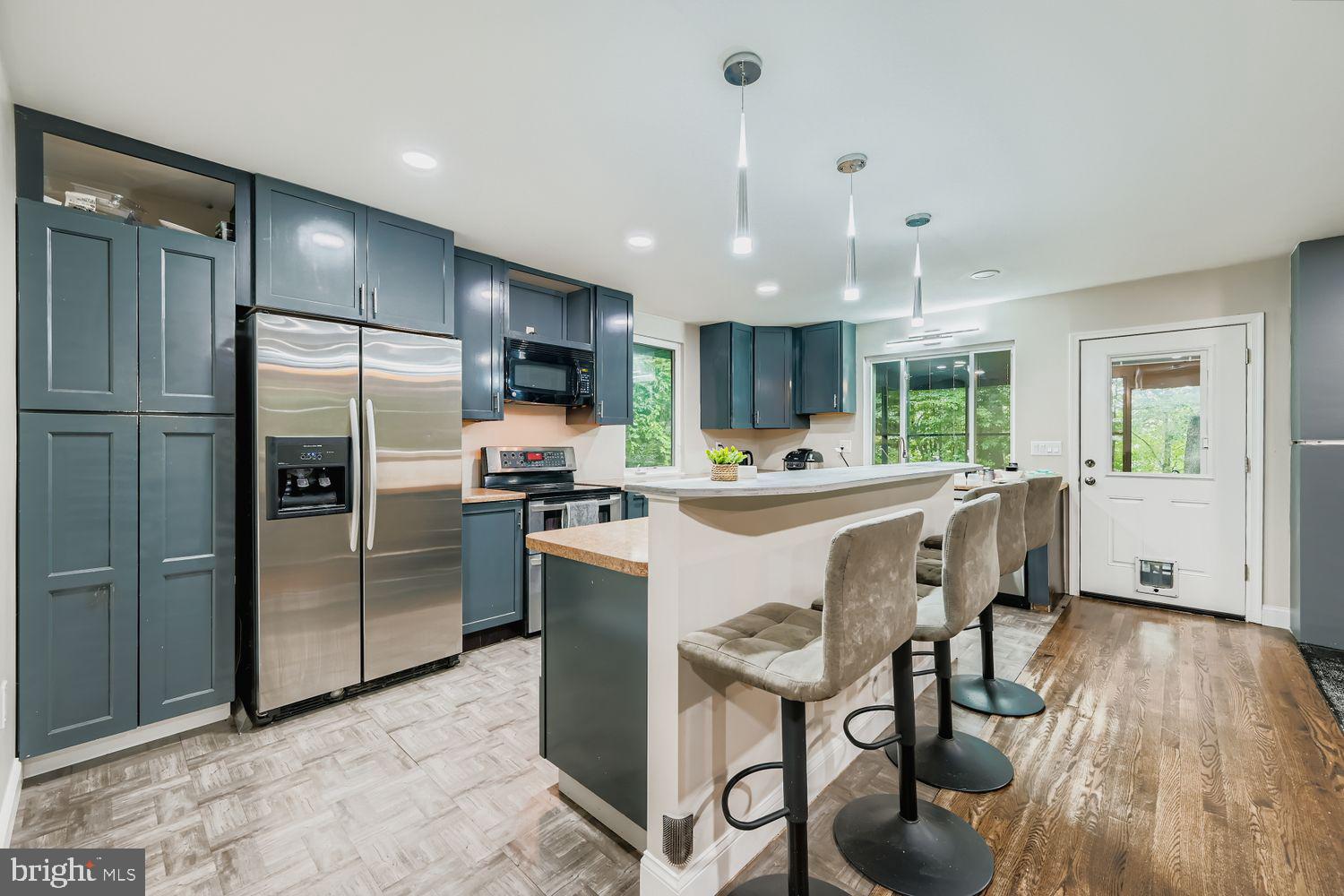 3203 Brezina Place Edgewater, MD 21037 - Photo 12 of 42 a kitchen with stainless steel appliances kitchen island granite countertop a refrigerator a stove a sink a dining table and chairs with wooden floor