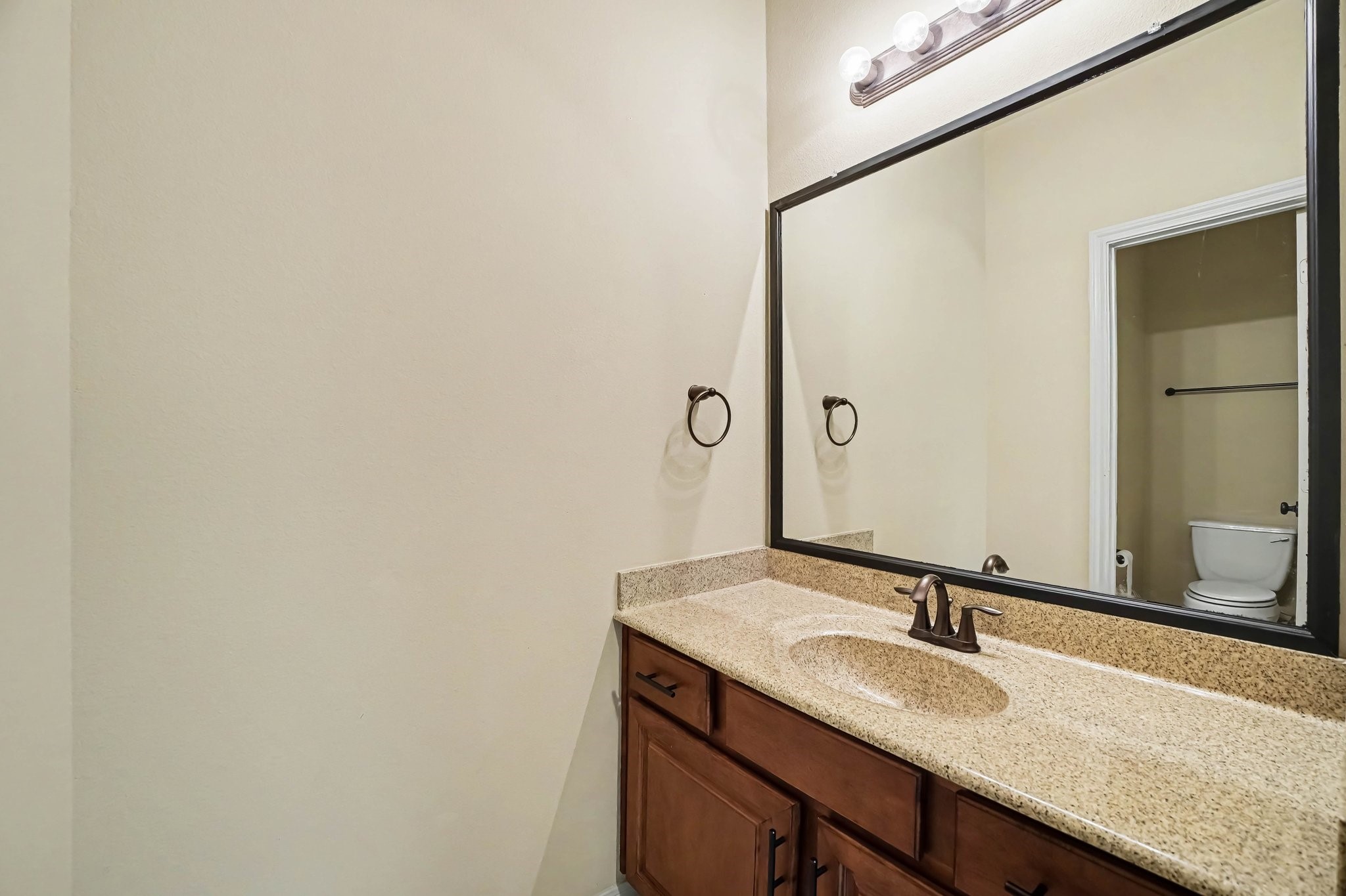 62 Sandwell Place Spring, TX 77389 - Photo 32 of 50 Spacious bathroom featuring a large granite countertop with elegant fixtures and ample cabinetry, complemented by a full-width mirror.