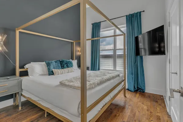 a bedroom with a bed and a flat tv screen on a dresser