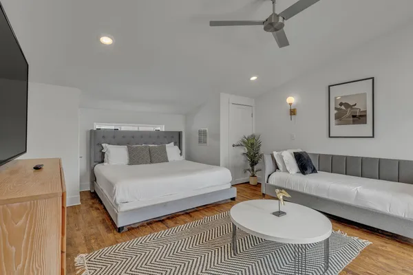 a bedroom with a bed a couch and wooden floor