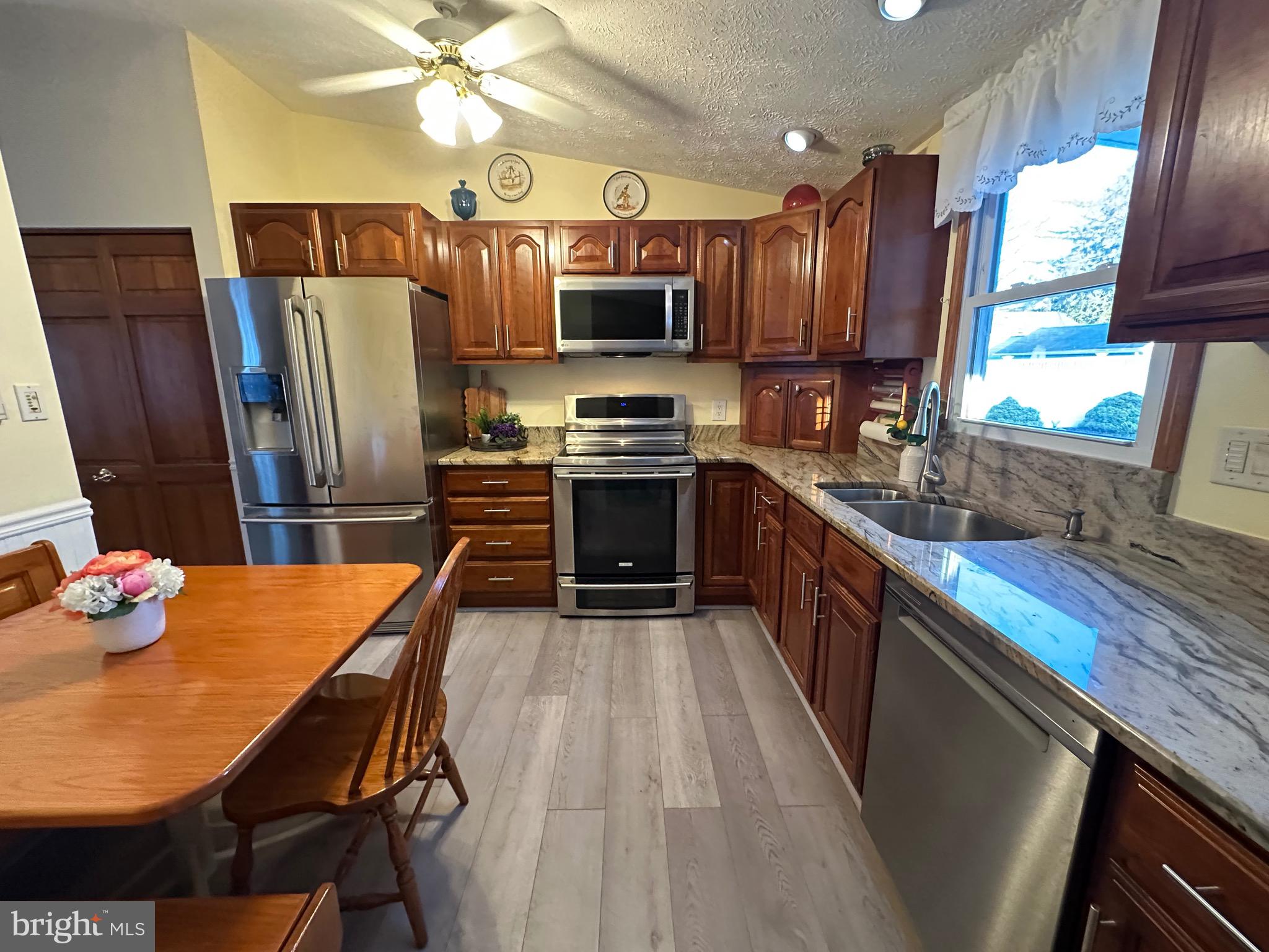 13 Cinder Road Lutherville-Timonium, MD 21093 - Photo 10 of 28 a kitchen with stainless steel appliances granite countertop a refrigerator a stove top oven a sink dishwasher and wooden cabinets with wooden floor