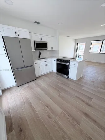 a view of a kitchen with wooden floor and electronic appliances