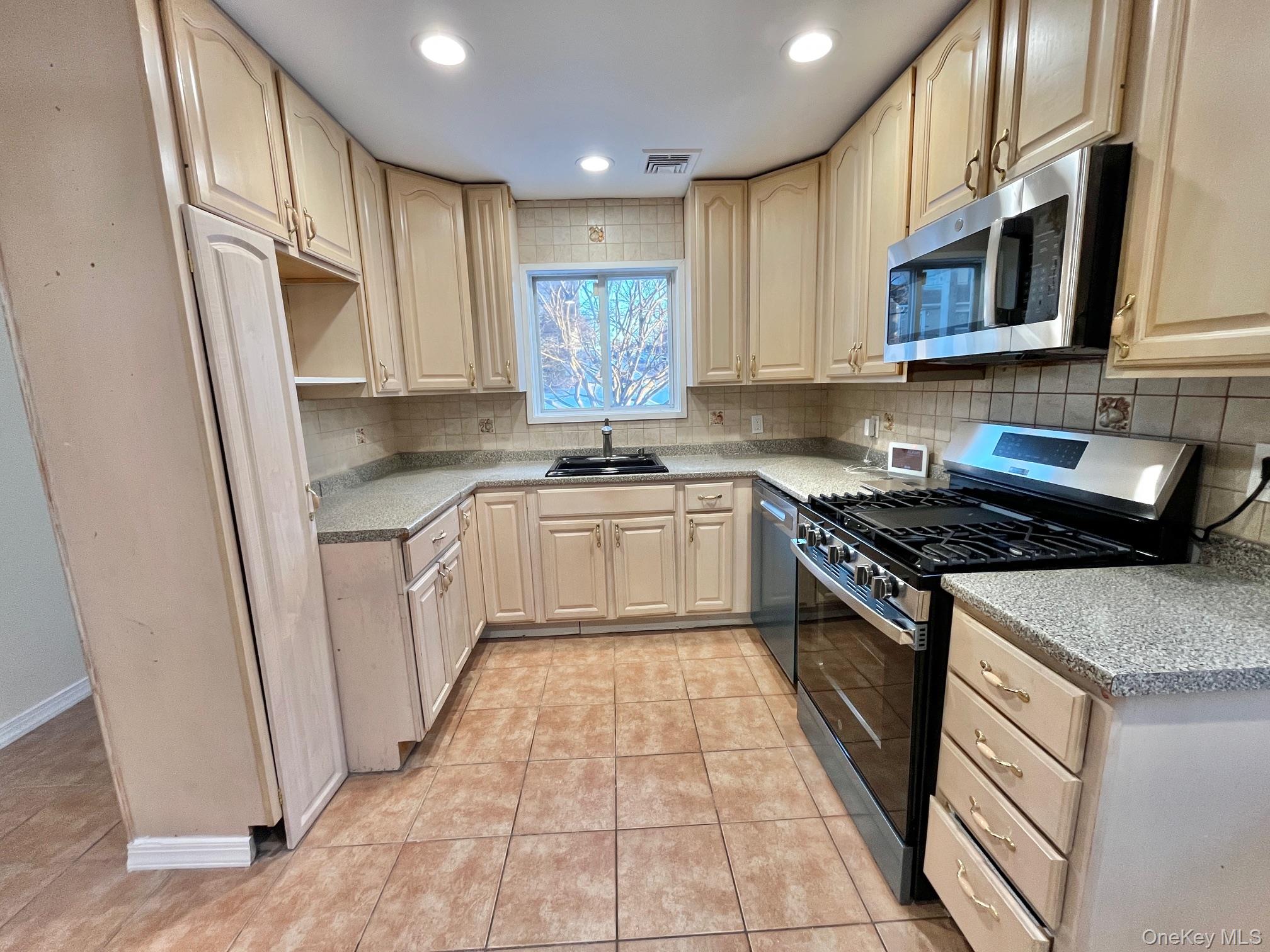 51 Emmett Terrace, Unit 1 New Rochelle, NY 10805 - Photo 2 of 23 a kitchen with stainless steel appliances granite countertop a stove top oven a sink dishwasher a refrigerator and cabinets with wooden floor