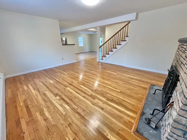 a view of an empty room with wooden floor and stairs