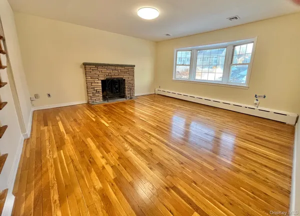 a view of an empty room with wooden floor and a fireplace
