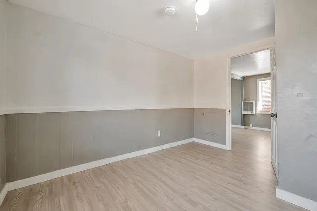 a view of empty room with wooden floor and fan