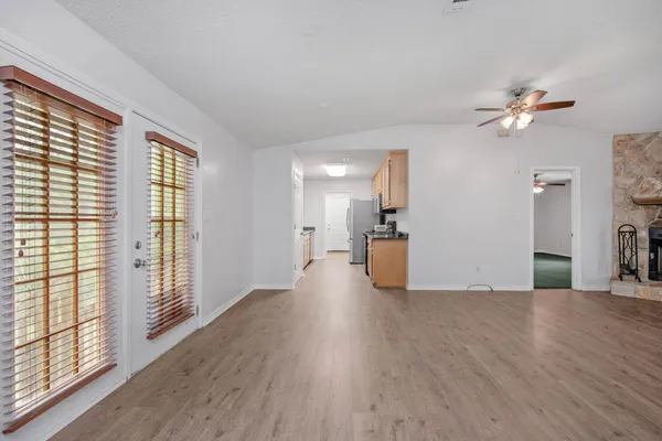 an empty room with windows fireplace and wooden floor