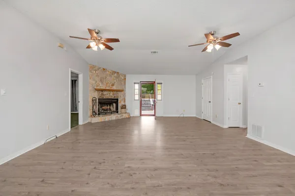 a view of a livingroom with a fireplace a ceiling fan and windows