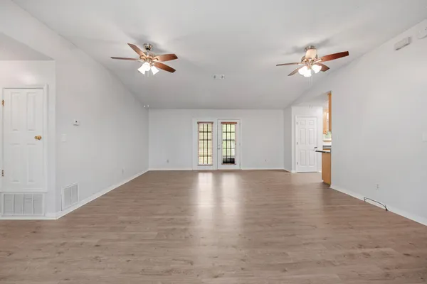 an empty room with windows and chandelier fan