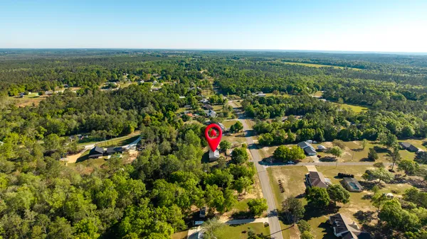an aerial view of residential houses with outdoor space and trees