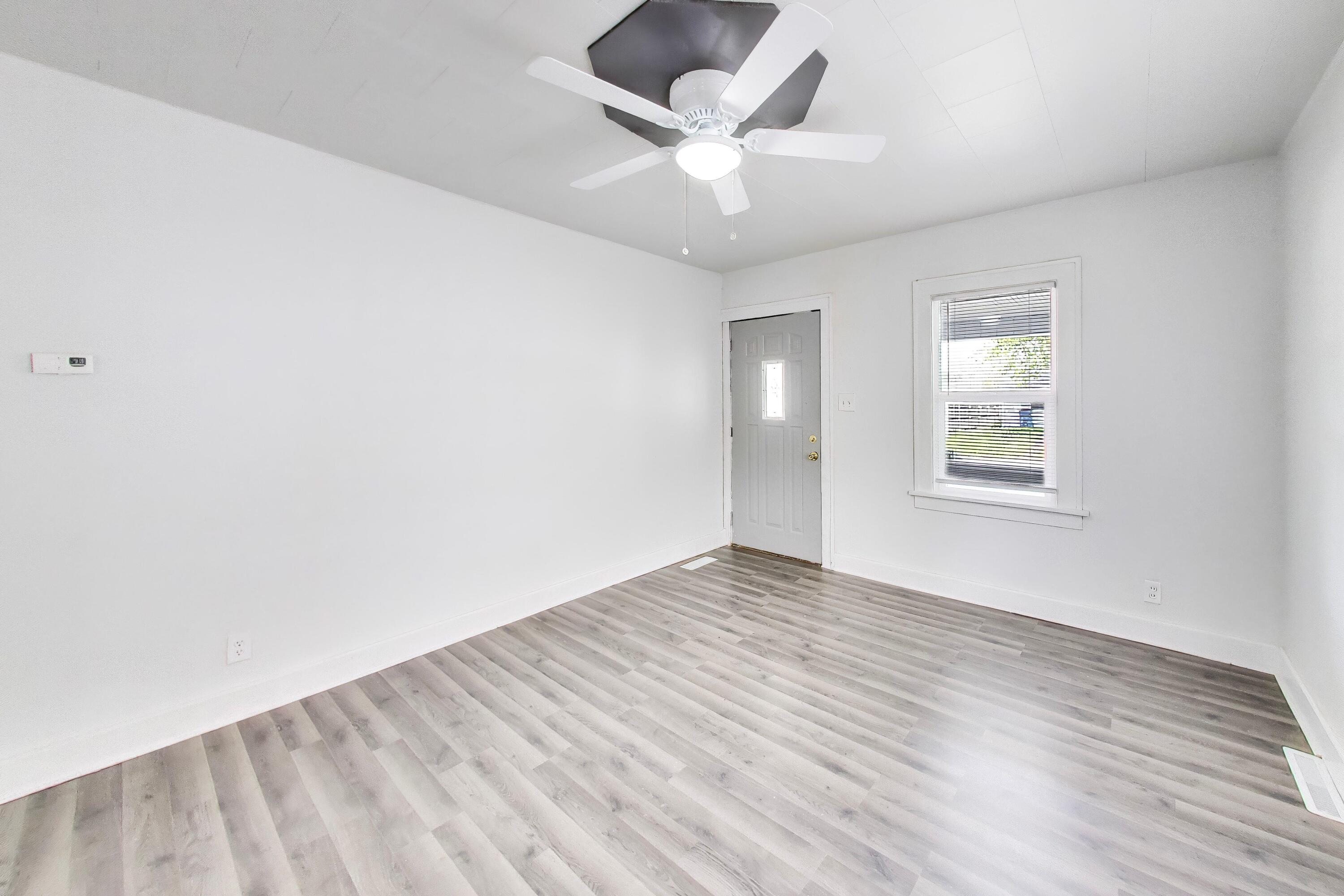 121 Faulkner Street Michigan City, IN 46360 - Photo 5 of 15 an empty room with wooden floor chandelier fan and windows