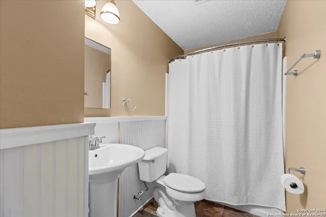a bathroom with a sink a toilet and shower curtain
