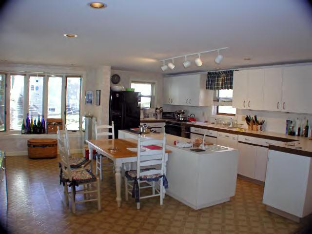 262-264 Kibbe Road Otis, MA 01029 - Photo 7 of 16 a room with stainless steel appliances kitchen island granite countertop a table chairs and a refrigerator