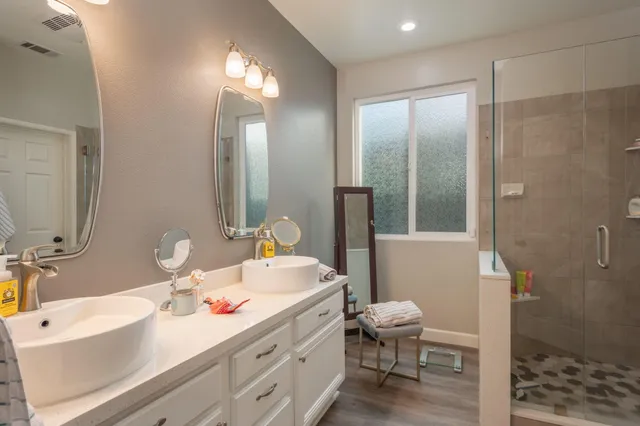 a bathroom with a double vanity sink toilet mirror and shower