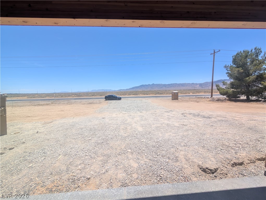 1120 West Gamebird Road Pahrump, NV 89048 - Photo 5 of 36 An arid landscape unfolds with mountains in the distance, framing a vast, clear sky.