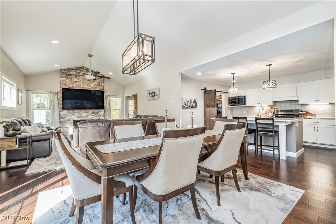 Dining room featuring a barn door, dark hardwood / wood-style floors, a healthy amount of sunlight, and vaulted ceiling