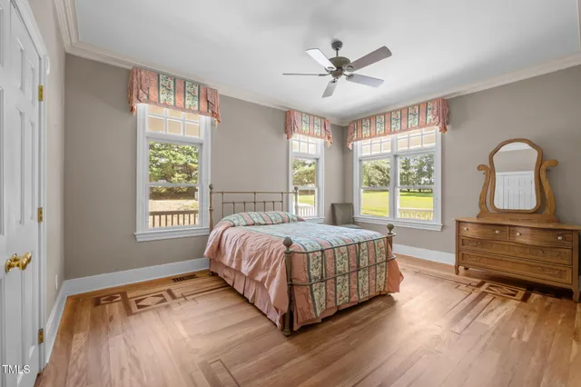 a bedroom with a bed and dresser with wooden floor