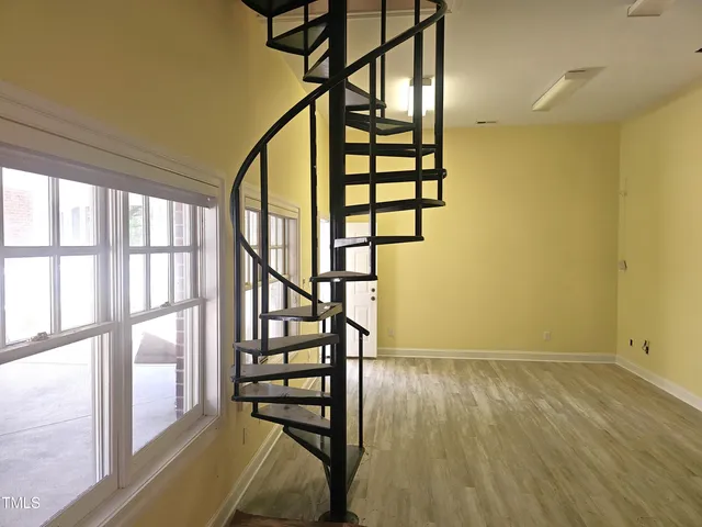 a view of a brick house with plants and large trees