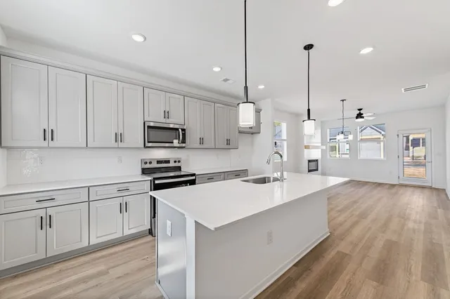 a large kitchen with cabinets wooden floor and stainless steel appliances
