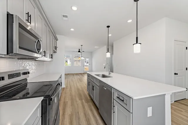 a kitchen with stainless steel appliances granite countertop a sink a stove and a wooden floors