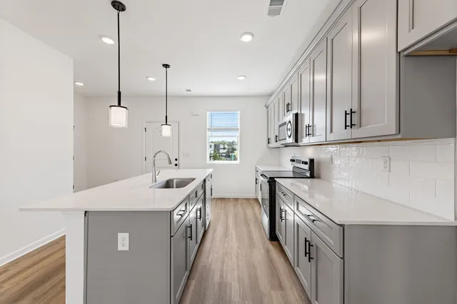 a kitchen with stainless steel appliances granite countertop a sink a stove and a wooden floors