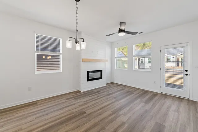 a view of an empty room with a window and wooden floor