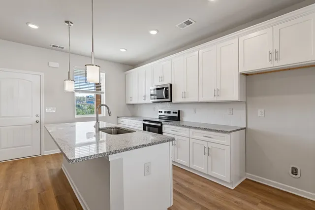 a kitchen with kitchen island granite countertop a sink a counter space appliances and cabinets