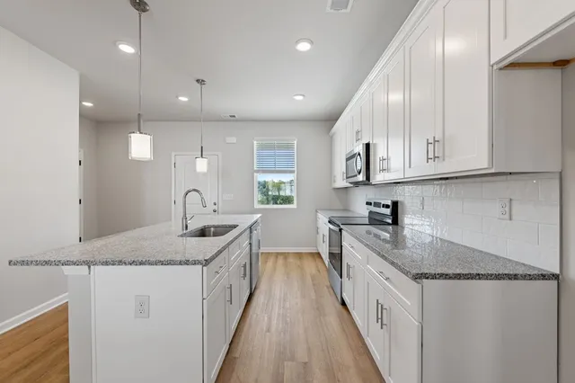 a kitchen with stainless steel appliances granite countertop a sink stove and cabinets