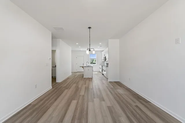 a view of a room with wooden floor kitchen view and a window