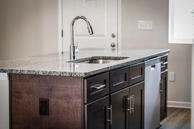 a kitchen with granite countertop a sink cabinets and stainless steel appliances