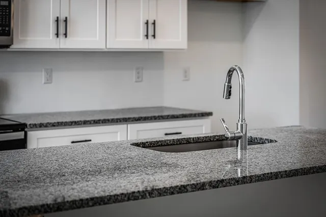 a kitchen with granite countertop a sink and a stove