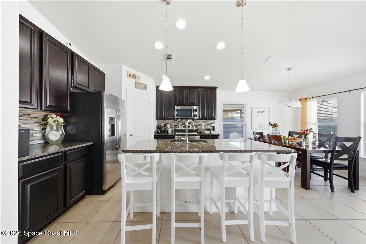 3258 Olivera Way St. Cloud, FL 34772 - Photo 16 of 30 a kitchen with stainless steel appliances kitchen island granite countertop a stove top oven a sink dishwasher and a refrigerator