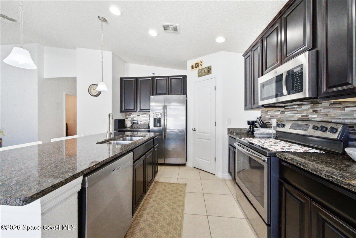 3258 Olivera Way St. Cloud, FL 34772 - Photo 17 of 30 a kitchen with stainless steel appliances granite countertop a stove a sink and a refrigerator