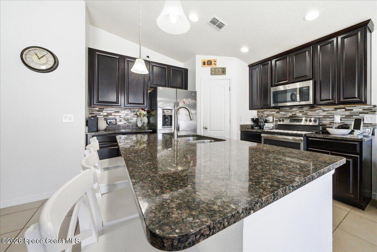 3258 Olivera Way St. Cloud, FL 34772 - Photo 18 of 30 a kitchen with stainless steel appliances granite countertop a sink a stove and a microwave